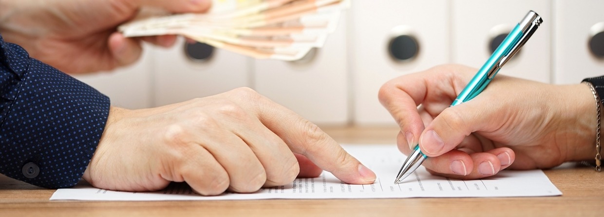 Kredietverstrekker met geld in zijn hand wijst aan waar te tekenen op het papier